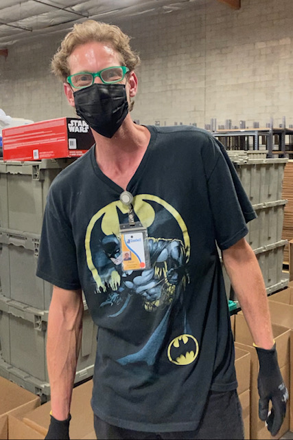 image of man stanfing wearing aface mask, black shirt with batman and wearing working gloves